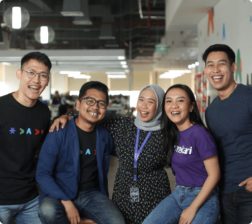 Group of young professionals poses together in a modern office space, showcasing a collaborative and friendly work environment.